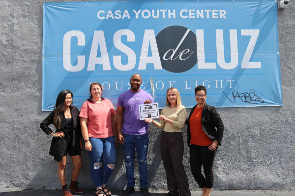 5 people in front of a wall with a casa de luz sign