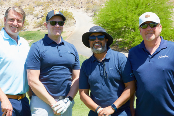 4 Men on a golf course smiling at the camera