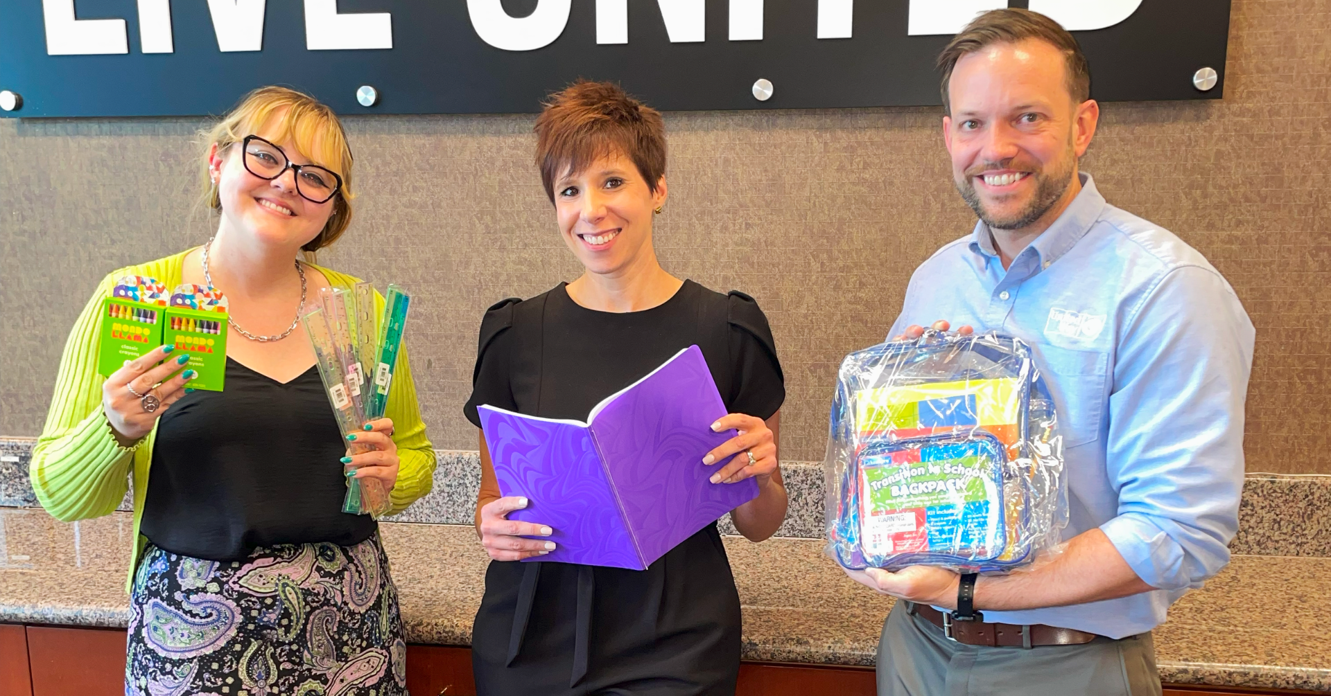Aurbie (left) Karen (middle) and Aaron (right) are smiling and posing with school supplies