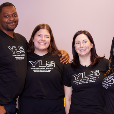 Four YLS members in front of purple wall with black and white YLS shirts.