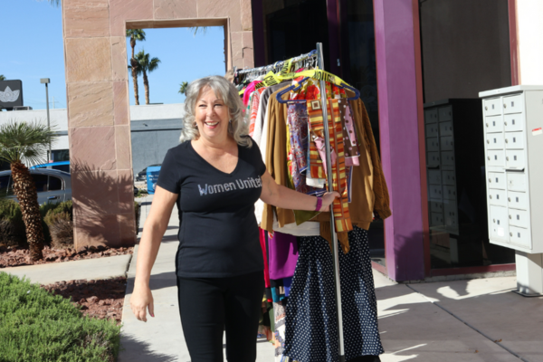 Woman with rack of clothes walking and smiling towards the camera