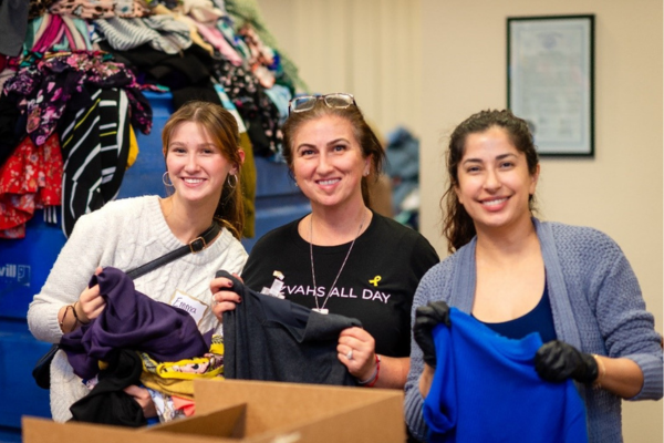 Volunteers holding up clothes and smiling