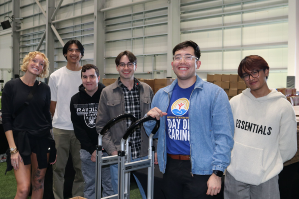 College students and UWSN Team Member smiling in front of packed boxes on field