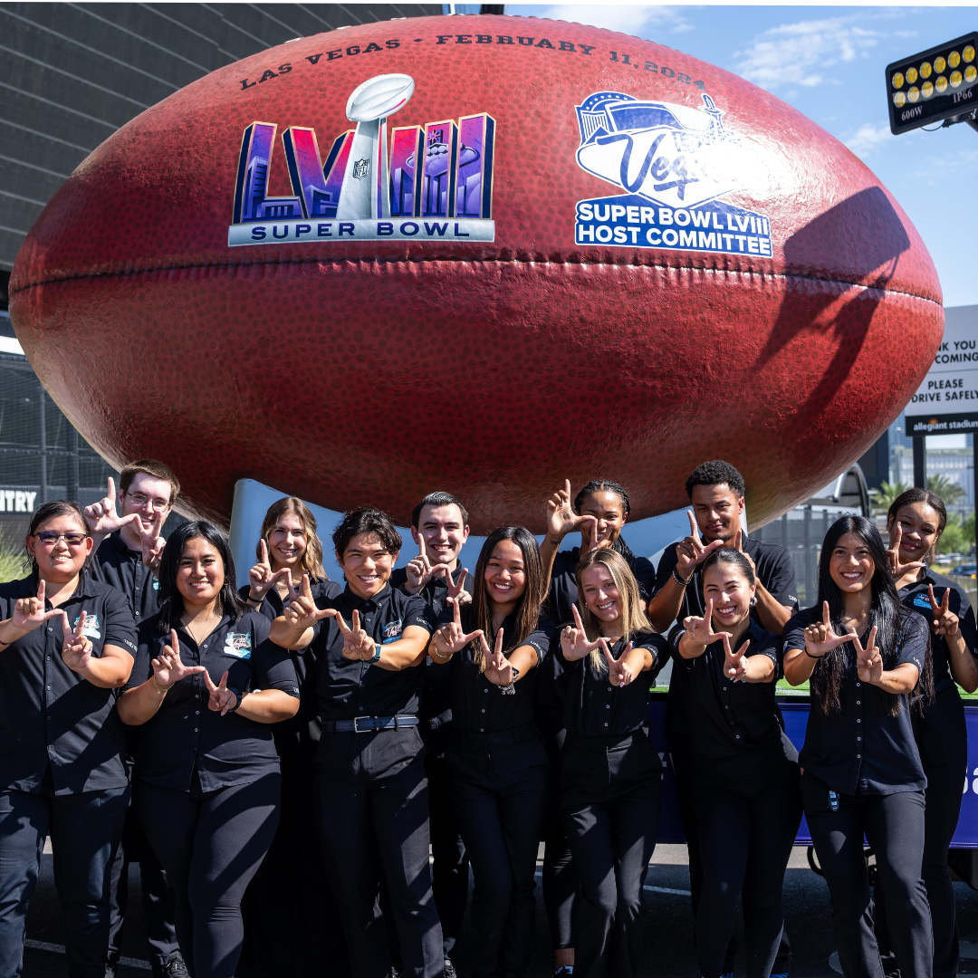 Group of students smiling in front of giant football