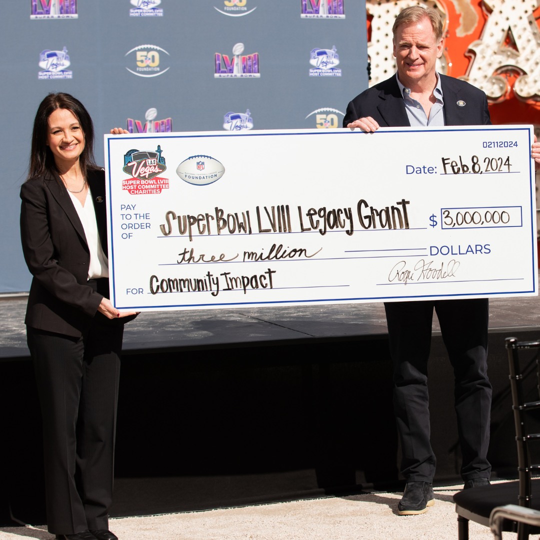 A man and a woman holding a large whiteboard check