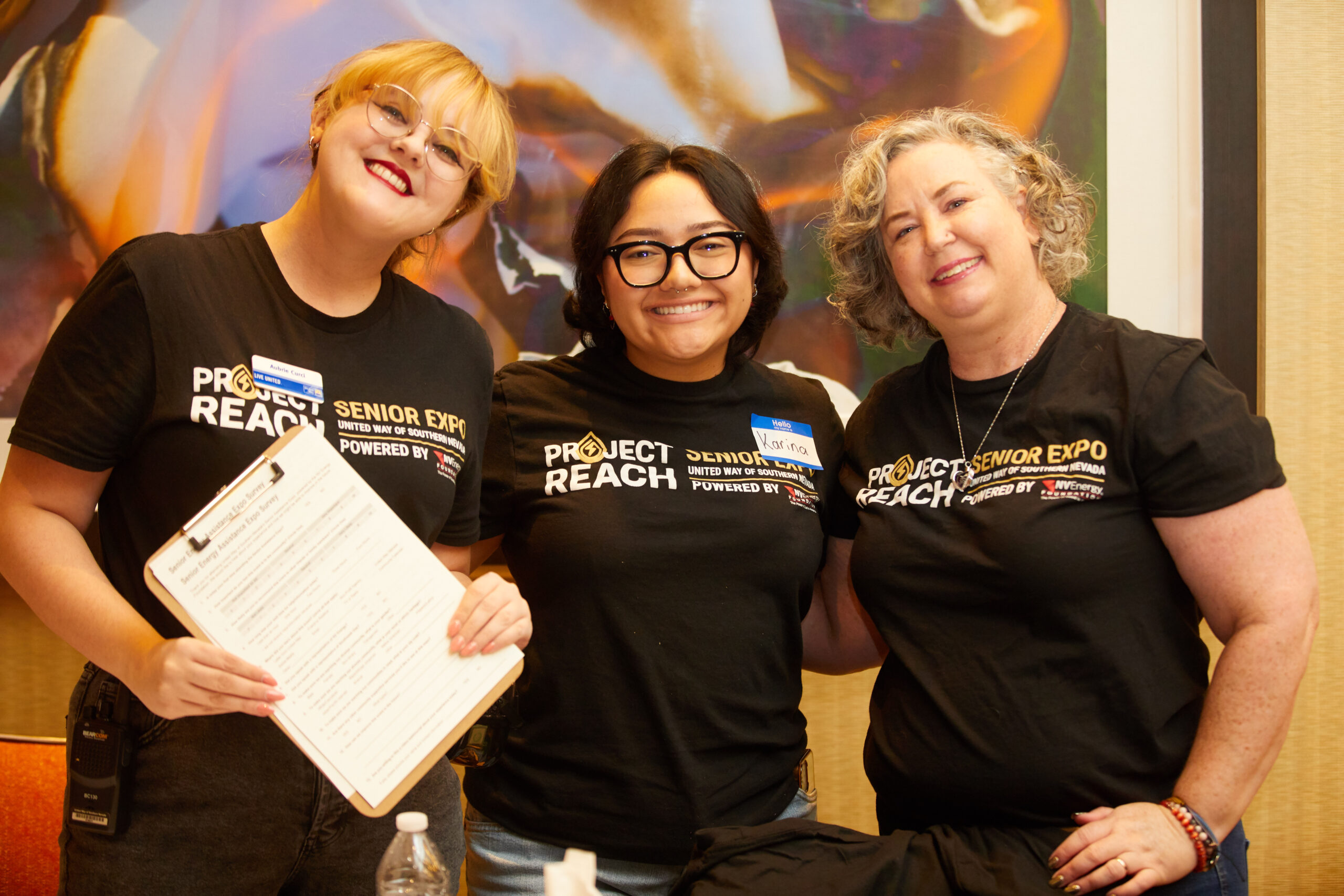 three people smiling and holding clipboards