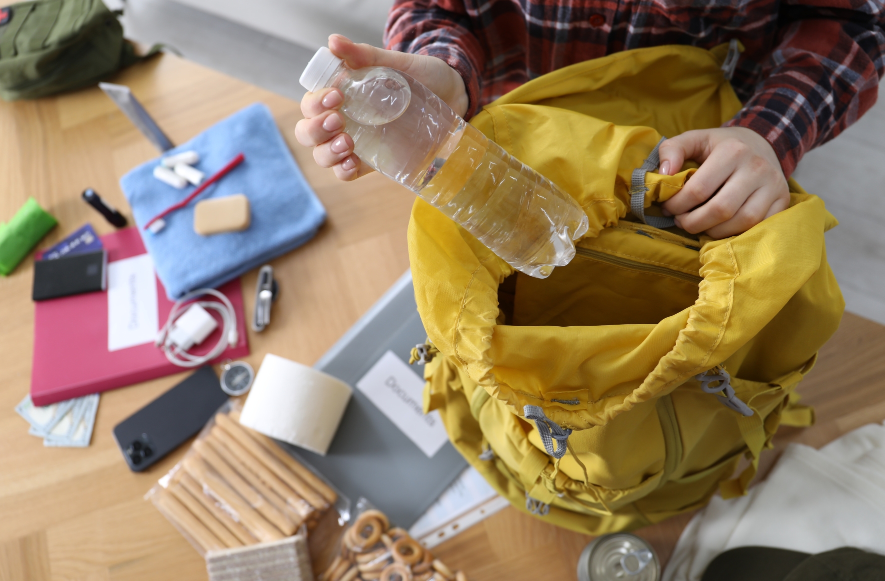 person packing disaster kit with essential supplies